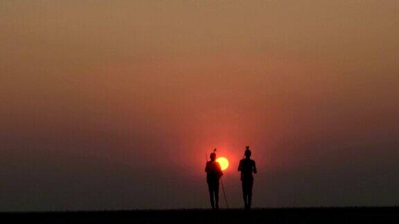 布须曼人在Makgadikgadipan的夕阳下行走