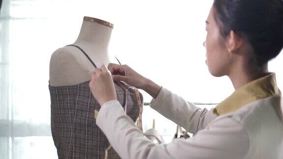 亚洲服装设计师的女人正在与尺寸和颜色图表