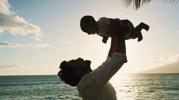 日落时分年轻的爸爸抱着孩子