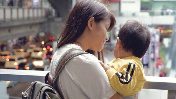 亚洲母亲抱着小男孩看着城市