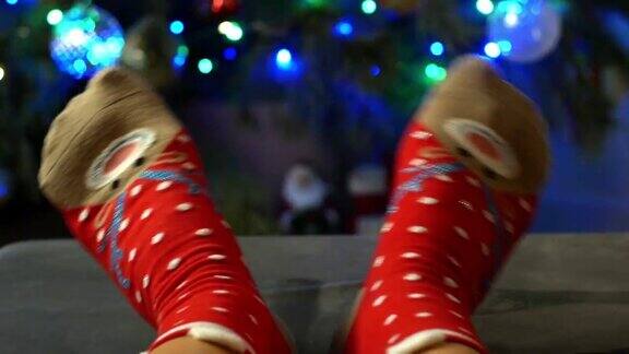 女人的腿在舒适的圣诞袜与鹿的背景装饰圣诞树圣诞袜子和圣诞树的特写4K圣诞视频
