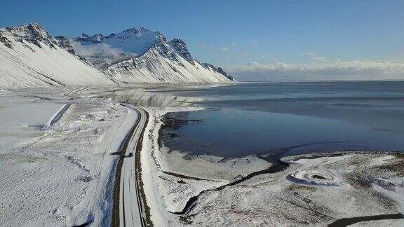 在冰岛东海岸的冬季飞过冰雪覆盖的道路和雪山景观