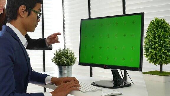 两个人对着绿色屏幕的电脑使用