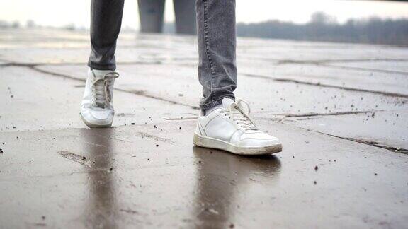 穿着白色运动鞋走在潮湿的瓷砖路上