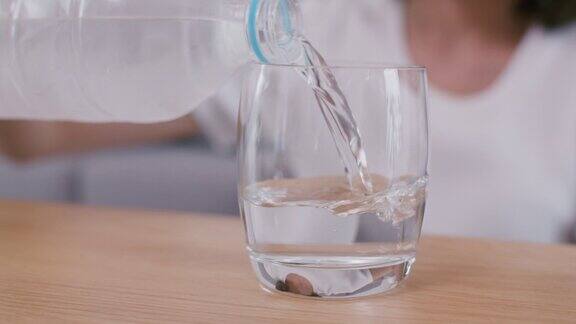 特写女子倒清冷水在一个玻璃杯