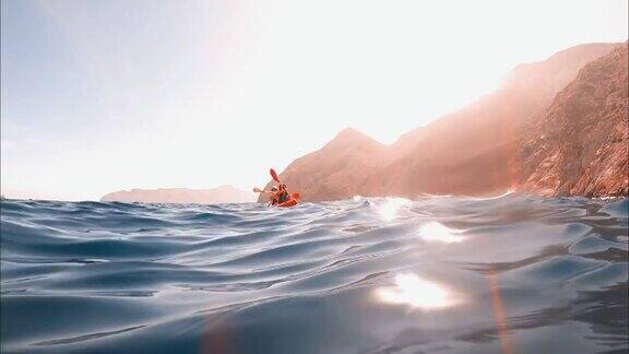 在西班牙卡塔赫纳的ElPortús一对夫妇在美丽的清澈的水中划皮艇皮艇运动员在双人皮艇练习运动夏季水上运动概念