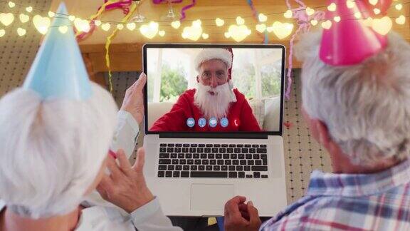 动画的童话灯在快乐的高加索老夫妇笔记本电脑视频通话与圣诞老人