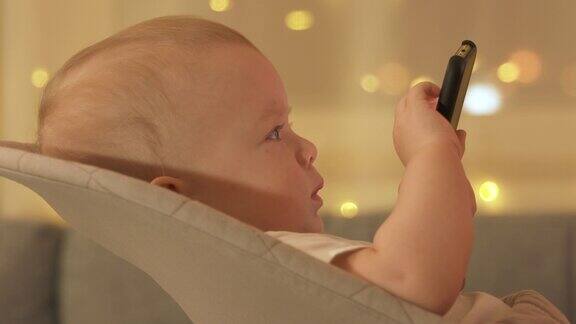 可爱的孩子在使用移动设备小男孩在电视上看电影同时使用智能手机