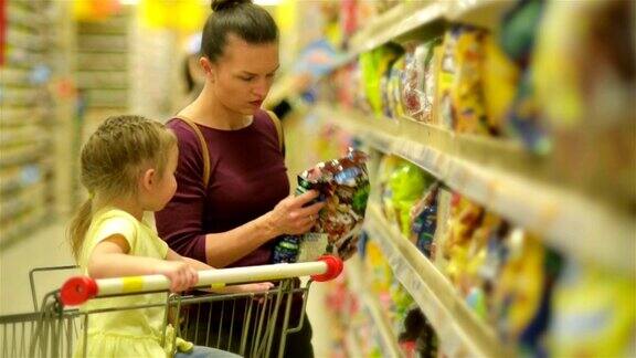 母亲和女儿在超市购物他们在买早餐片坐在超市购物车里的女儿