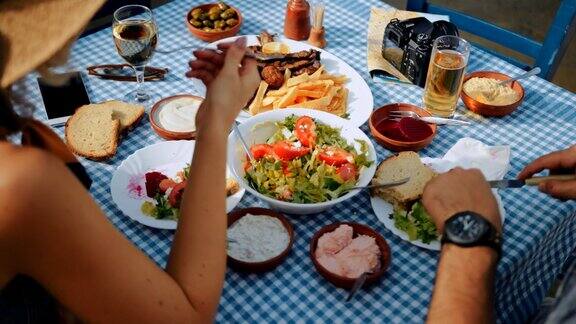 年轻的游客夫妇在传统的希腊餐馆吃午餐
