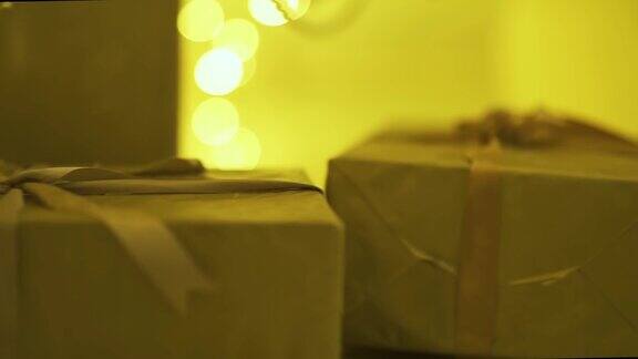 金色的礼盒上面有雪和丝带装饰圣诞冬季假期呈现抽象的散景闪烁模糊灯光背景