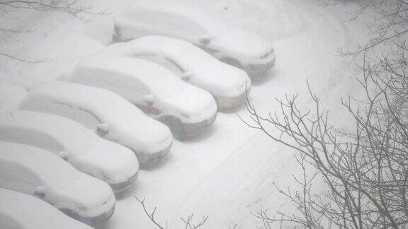 下雪时住宅区停车场上的汽车被雪覆盖