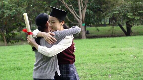 年轻的亚洲女毕业生在毕业典礼上拥抱她的朋友国际多元化背景