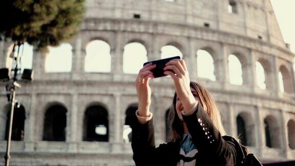 年轻美女用智能手机自拍走在意大利罗马斗兽场附近的女子
