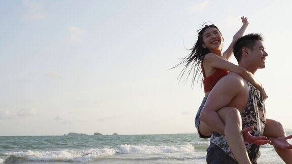 亚洲年轻的男人和女人有乐趣一起在海滩上玩迷人的新婚夫妇在海边散步和跑步时感到幸福在热带海岛享受假期蜜月旅行