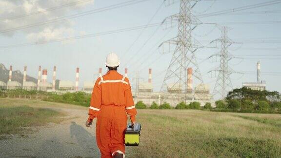 亚洲专业女工程师戴着防护头盔行走在火电厂上电、生态、技术