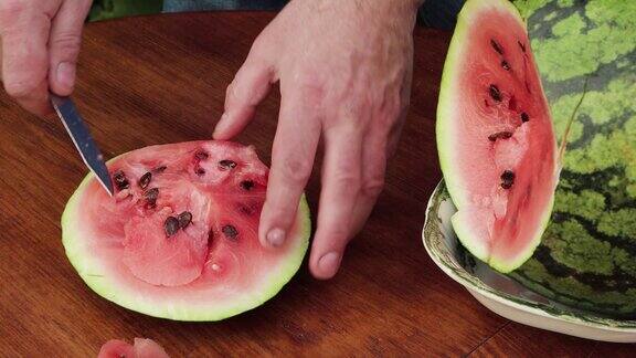 一名男子用刀切下西瓜的粉红色果肉