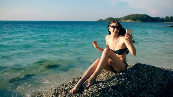 年轻快乐的女人与朋友通过互联网使用智能手机在海洋海滩聊天