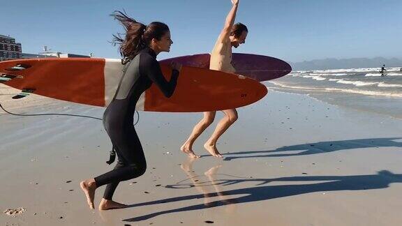 一对兴奋的情侣冲进大海用冲浪板冲浪