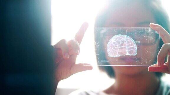 一名亚洲女性手持人类大脑的技术数字全息界面人工智能