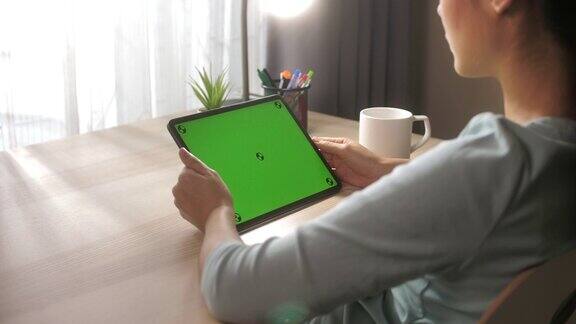 特写手使用数字平板电脑与绿色屏幕在桌上在家