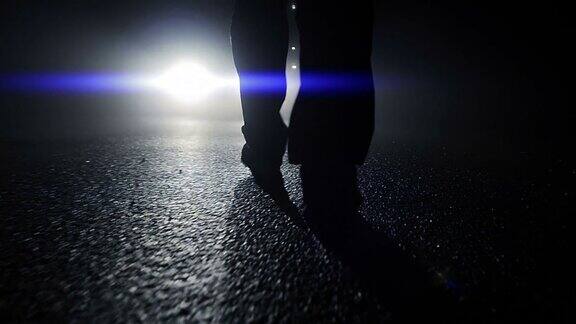 黑暗中一个人站在汽车前的轮廓有阴影和背光的夜晚