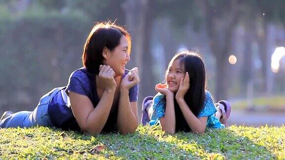 快乐的亚洲母亲和女儿在草地上