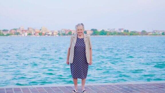 一个老妇人站在威尼斯泻湖旁看着摄像机