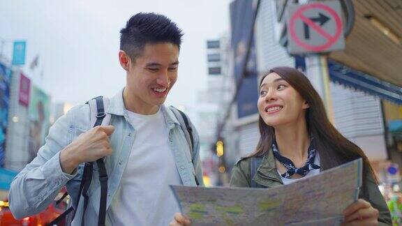 亚洲情侣在这个城市度蜜月年轻的新婚夫妇背包客们用地图找到目的地一起享受度假的时光