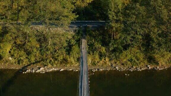 木制吊桥横跨在秋天的山脉的河流上