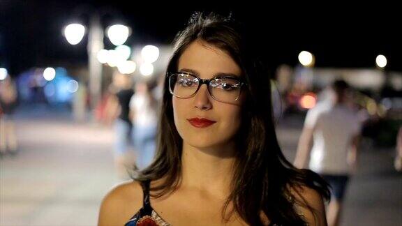 年轻漂亮的女人晚上站在街上看着镜头