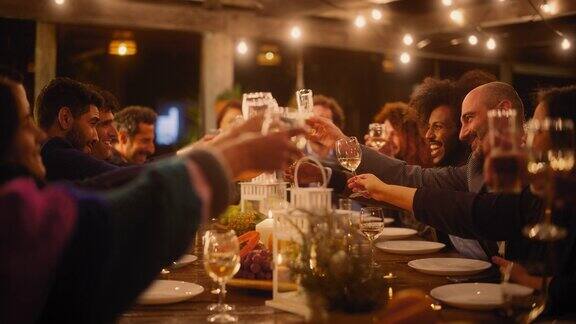在餐厅里举办一场盛大的晚宴与少数来自不同种族的朋友一起庆祝美丽快乐的主人在晚上坐在桌子旁时提议敬酒并举起酒杯