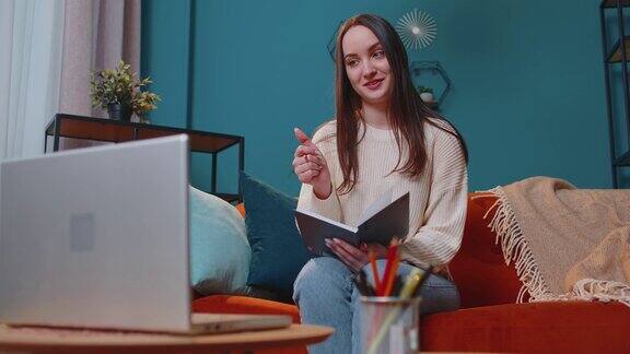成年女学生在家里用笔记本电脑进行视频会议对着网络摄像头通话
