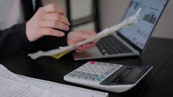 女人在家里或办公室的客厅里检查账单、税收、银行账户余额和计算开支特写镜头