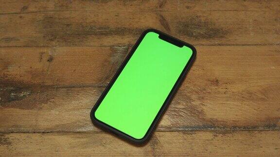 绿色屏幕的手机放在木桌上