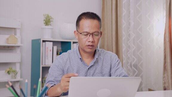 一名亚裔男子年龄40-50岁穿着休闲使用电脑