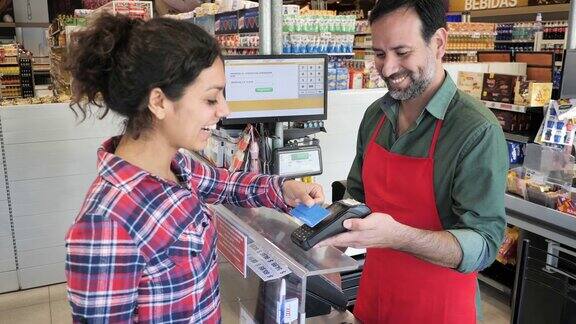 超市收银员-女性顾客用非接触式信用卡付款