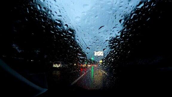 夜雨在城中行驶时光流逝夜晚的道路POV透过挡风玻璃看雨点在夜晚的城市时光流逝