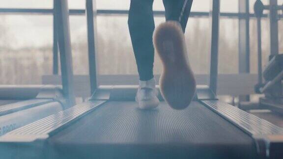 特写运动员在健身房里跑步机上跑步慢动作在跑步机上锻炼的白色运动鞋的后视图低视人的腿训练在运动俱乐部