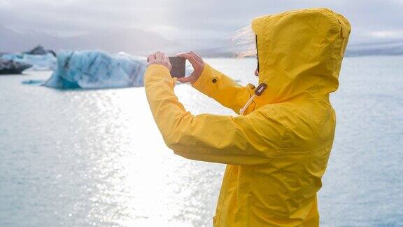 一名女子在冰川湖中拍摄冰山的照片