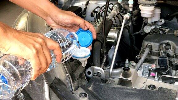 小车射击汽车维修技工向汽车发动机部件玻璃的喷射水瓶注水