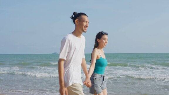 亚洲年轻男女在沙滩上玩得很开心迷人的新婚夫妇感到快乐在海边散步和跑步享受假期蜜月旅行在热带海岛