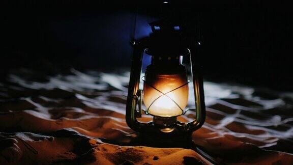 古老的油灯站在沙滩上在黑暗中闪闪发光