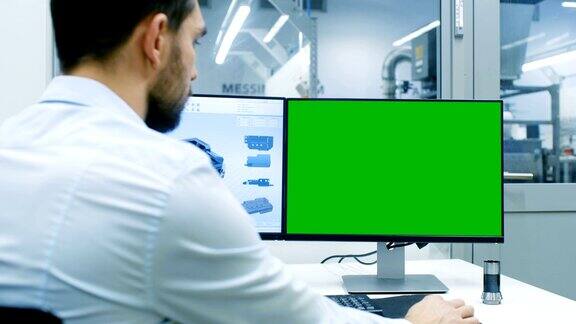 工程师工作在一个个人电脑上的绿色屏幕模型屏幕上他正在设计新的CAD程序组件可见办公室外窗口组件制造工厂