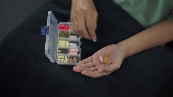 亚洲妇女从药片容器中取出药片