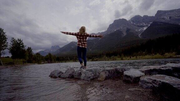 年轻女子在山湖上跳起了一块又一块的石头