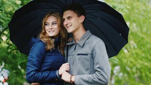 一对恩爱的情侣在伞下等待雨停
