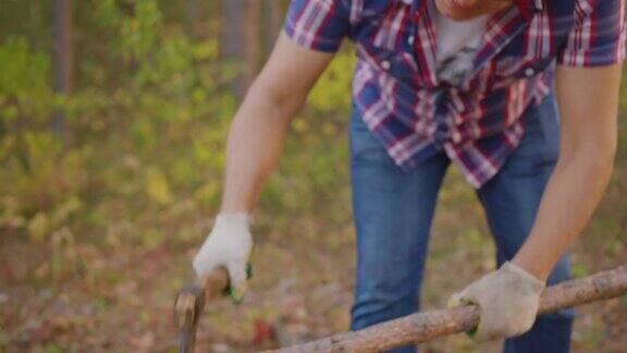 一个成年人在夏日的森林里用斧头砍柴穿着格子衬衫的伐木工用斧头在夏天的森林里劈柴