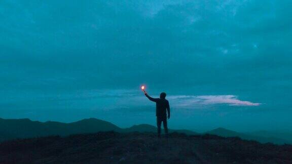 雄鸟拿着烟火棒站在夜山上