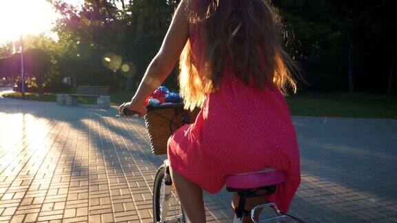 年轻迷人的女孩骑在老式自行车在公园日落近距离